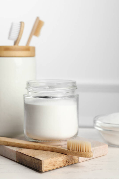 Bamboo toothbrushes and jar of baking soda on white table - Valokuva, kuva