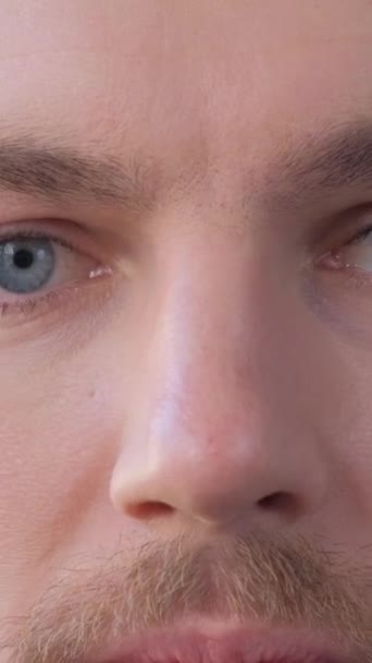 Close-up of the face of a European man looking into the camera and slowly closing his eyes. Portrait of a handsome young man. Vertical video - Materiał filmowy, wideo