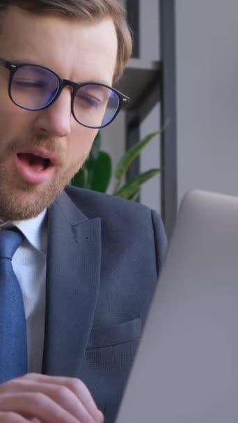 A tired manager is napping and yawning at work while using a laptop. Vertical video - Felvétel, videó
