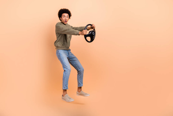 Full size profile photo of impressed person jumping open mouth hold wheel empty space isolated on beige color background. - Φωτογραφία, εικόνα