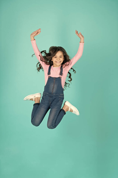 childhood of teen girl jumping on background. childhood of teen girl. childhood of teen girl isolated on blue. childhood of teen girl in studio. - Foto, afbeelding
