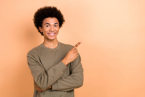 Portrait of optimistic handsome young person afro hairdo dressed khaki shirt indicating empty space isolated on beige color background. - Photo, image