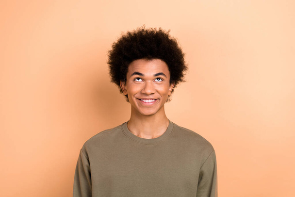 Portrait of cheerful young person with afro hairdo wear khaki shirt look up empty space dentistry ad isolated on beige color background. - Φωτογραφία, εικόνα