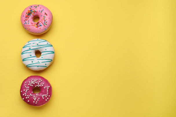 Tasty glazed donuts on yellow background, top view. Space for text - Photo, Image