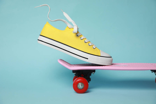 Yellow classic old school sneaker on skateboard against light blue background - Foto, afbeelding