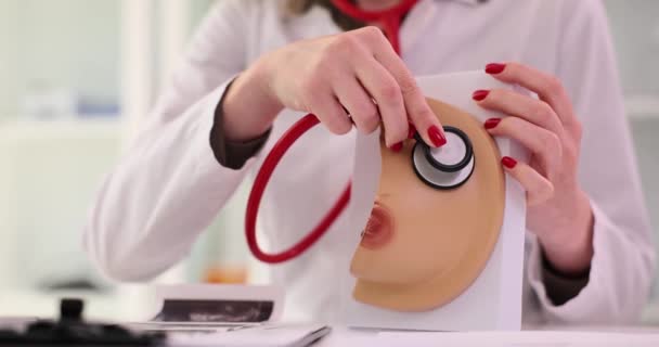 Arzt wendet Stethoskop auf realistisches Brustmodell in Klinik an. Erkrankungen der Brustdrüsen verursachen Prävention und Behandlung - Filmmaterial, Video