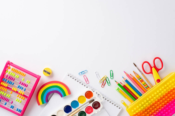 Step into the enchanting realm of early education with this top-down photograph: a delightful display of colorful school supplies against a white background, ready for text or advert placement - Photo, Image