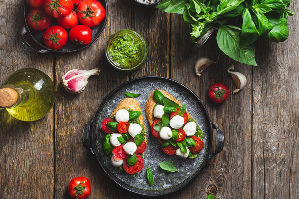 Bruschetta met mozzarella, tomaten, basilicum en pesto in een bord. Bruschetta Caprese - Foto, afbeelding