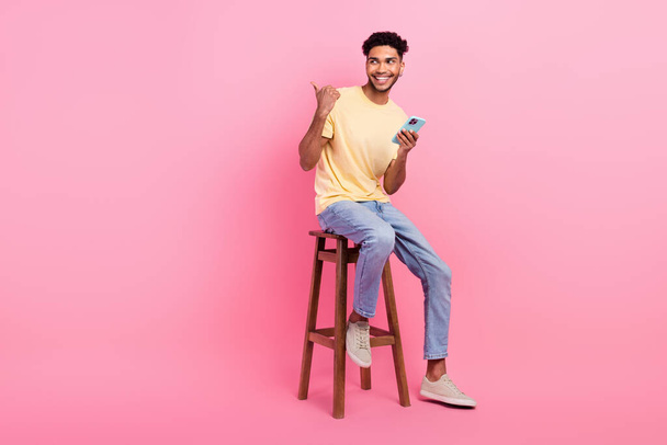 Full size photo of young guy sitting bartender direct finger novelty phone download app for friends chat isolated on pink color background. - 写真・画像
