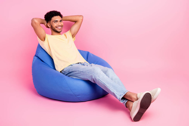 Full length body photo of young handsome guy sitting pouf hands head take nap pause relaxation rest isolated on pink color background. - Фото, изображение