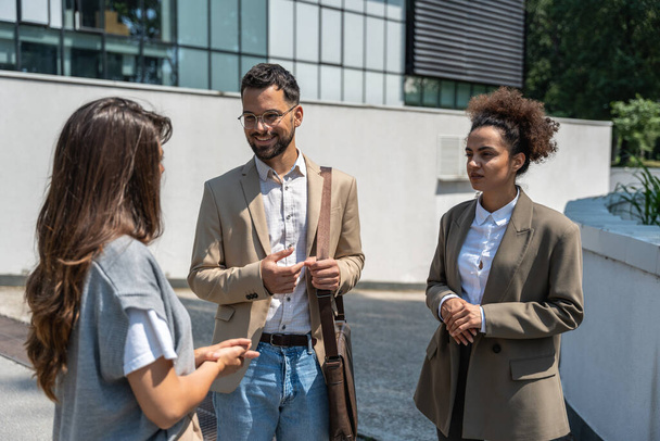 Group of business people walk outside in front of office buildings. Businessman and two businesswomen sharing experience ideas and tactic for successful strategy and marketing. Workers taking a break. - Foto, Imagem
