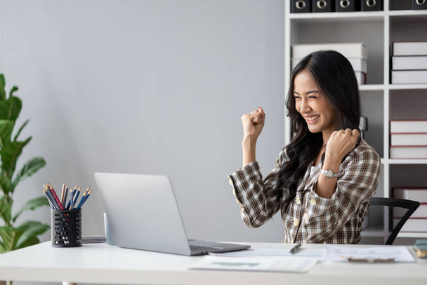 Beautiful Asian woman looking at data and showing happy expression, businesswoman is delighted to see the quarterly earnings summary on target. Management concept of a startup company. - Valokuva, kuva