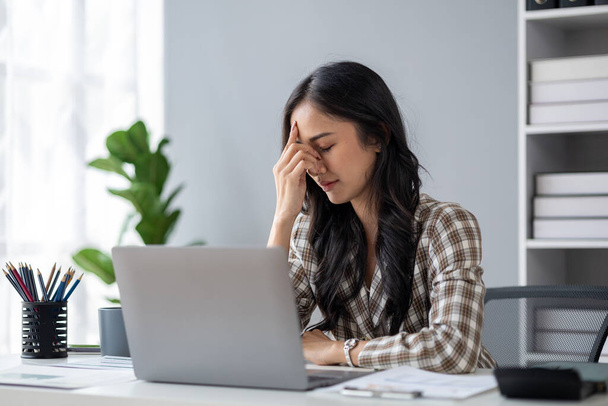 Beautiful asian woman suffering from stress due to working long hours and job problems, young business woman having office syndrome from overwork causing pain, headache. Office syndrome concept. - Fotoğraf, Görsel