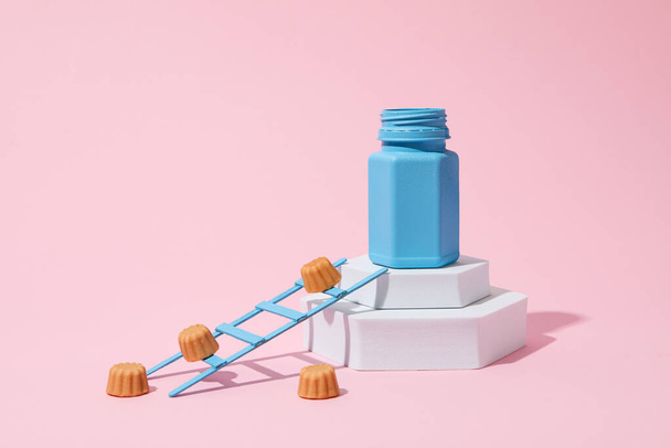 Blue jar on white blocks and jelly candy on pink background - Foto, Imagen