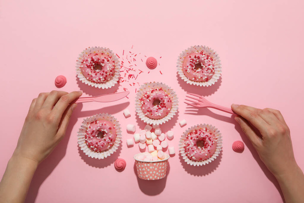 Muitos donuts rosa em um fundo rosa com as mãos - Foto, Imagem
