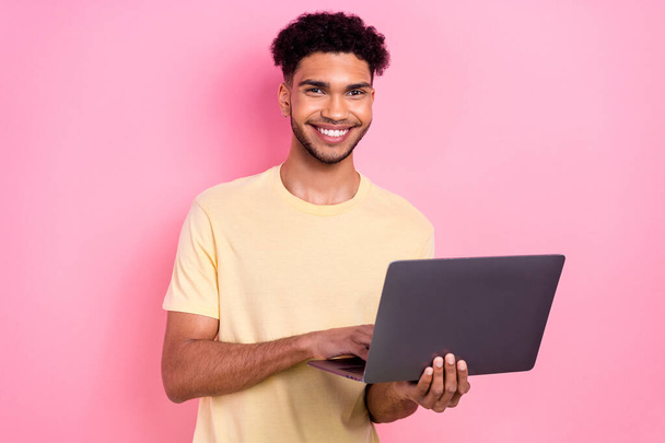 Photo of cheerful toothy beaming intelligent guy dressed yellow stylish t-shirt texting email on laptop isolated on pink color background. - Фото, зображення