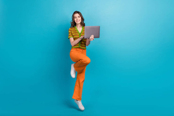Full length photo of gorgeous smart girl wear orange pants colorful cardigan hold laptop texting letter isolated on blue color background. - Foto, imagen