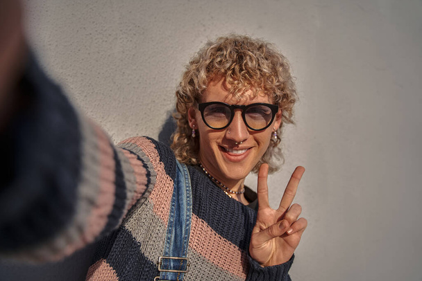 Waist up portrait of caucasian trendy guy in stylish clothes making selfie and smiling. Youth and people lifestyle concept - Fotografie, Obrázek