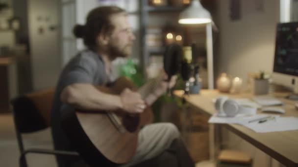 Размытый средний кадр музыканта, играющего на гитаре и поющего в микрофоне в домашней студии звукозаписи - Кадры, видео