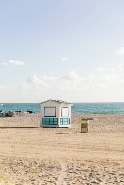 Una cabaña de salvavidas se levanta en una playa de arena cerca del océano, ofreciendo protección y asistencia a los asistentes a la playa.. - Foto, imagen