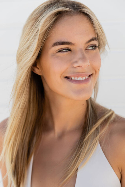 Egy fiatal szőke nő hosszú hajjal melegen mosolyog a kamerába egy napsütéses napon Miami Beach-en.. - Fotó, kép