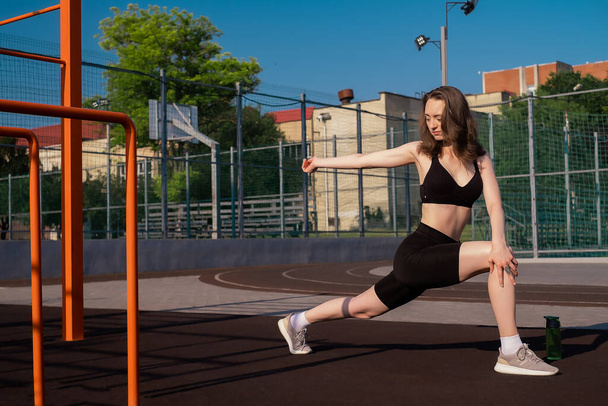 Sports girl doing morning workout and stretching on street sports ground. Fitness training on the sports ground, healthy lifestyle, athletic body - Photo, Image