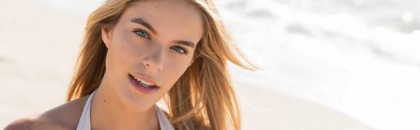 Une jeune, belle femme blonde posant dans un haut de bikini sur une plage de sable fin de Miami sous le soleil éclatant, respirant la confiance. - Photo, image