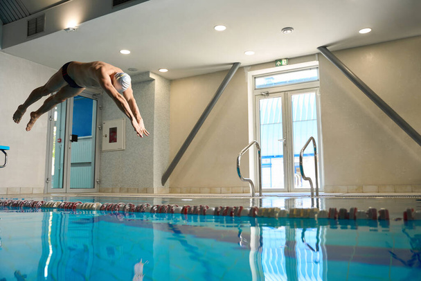 Felnőtt férfi belevetette magát a medencébe, profi sportoló foglalkozik sport úszás, gyakorlás - Fotó, kép