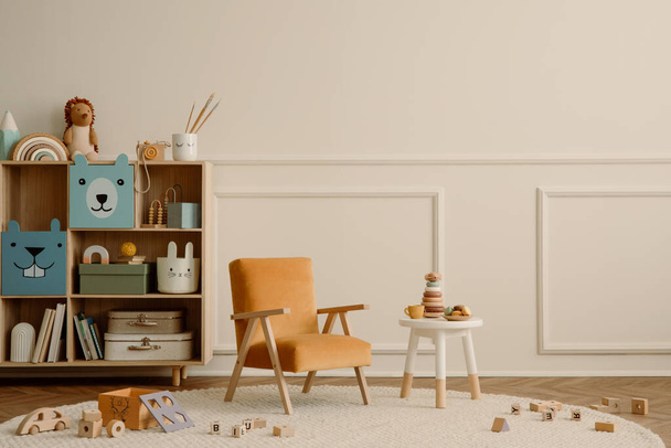 Minimalist composition of kid room interior with copy space, orange armchair, wooden sideboard, round stool, beige rug plush toys, wooden blockers ant personal accessories. Home decor. Template. - Foto, imagen