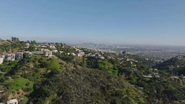 Voorwaarts vliegen boven luxe woonwijk in heuvels boven metropool. Los Angeles, California, Verenigde Staten. - Video