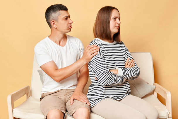 Family relationship problems. Brunette man gently touching woman shoulder after family fight, young husband ask upset wife for forgiveness after conflict. Sincere boyfriend feel sorry for argument. - Foto, Bild