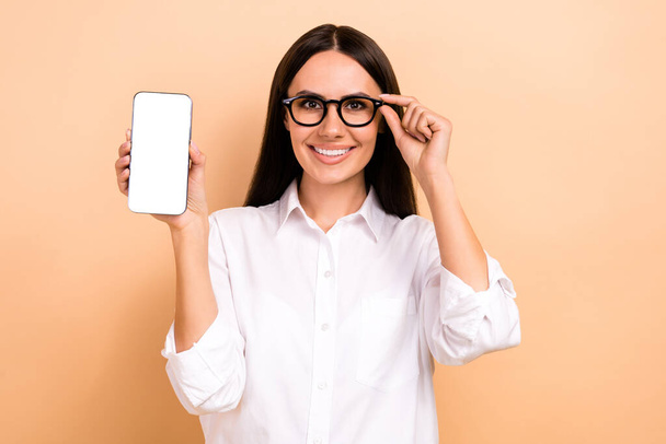 Photo of young good mood business woman wear white shirt hold smartphone empty space display sale online isolated on beige color background. - Foto, Bild