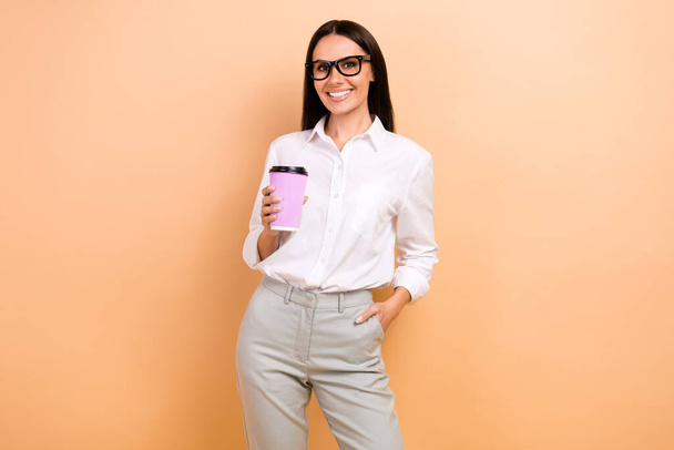 Photo of gorgeous cheerful classy person toothy smile arm hold fresh coffee cup isolated on beige color background. - Foto, imagen