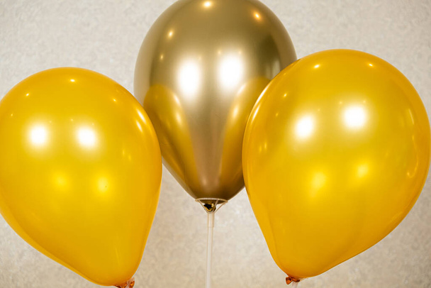 Three yellow balloons on a beige background. Birthday, organization of holidays - Photo, Image