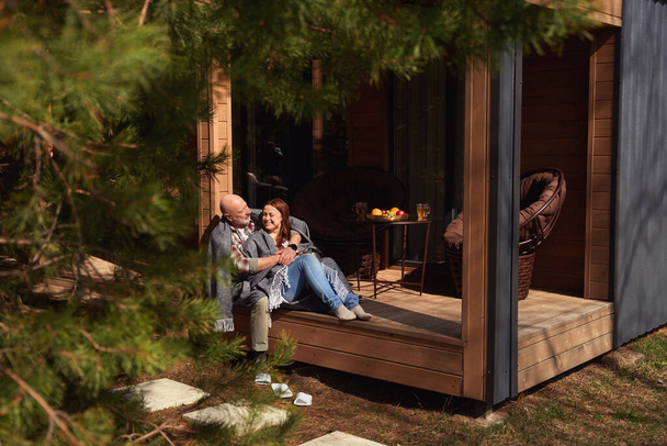 Agradable señora madura sentada en el porche en brazos del hombre amoroso - Foto, Imagen