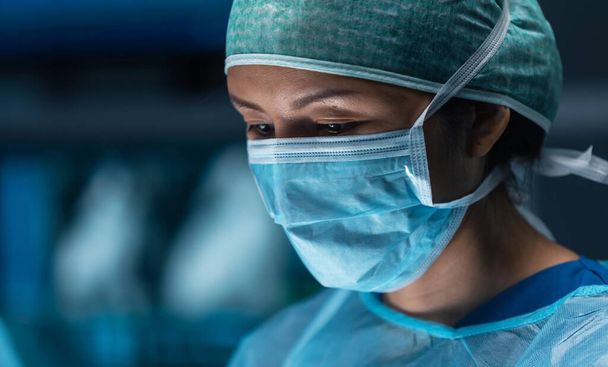 Diverse team of professional medical doctors performs a surgical operation in a modern operating room using high-tech equipment and technology. Surgeons are working to save the patient in the hospital - 写真・画像
