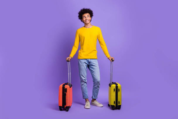 Full body photo of young thoughtful man holding luggage passenger waiting for his airplane look mockup isolated on violet color background. - Foto, Imagem