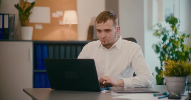 Αργή κίνηση του νεαρού επιχειρηματία που εργάζεται σε φορητό υπολογιστή κάθεται στο γραφείο στο γραφείο. - Πλάνα, βίντεο