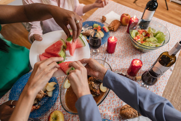 różnorodne ręce biorąc kawałek arbuza, obiad przychodzi w znajomych, którzy jedzą owoce - Zdjęcie, obraz