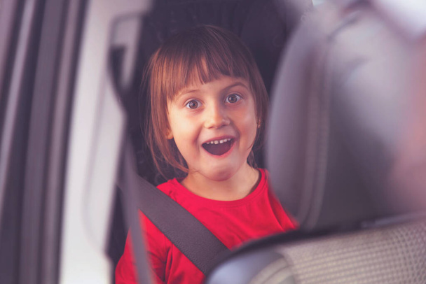 Koncepcja bezpieczeństwa. Happy cute little girl dziecko siedzi w foteliku samochodowym. - Zdjęcie, obraz