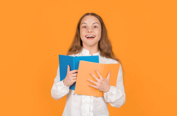 happy teen girl hold school workbook on yellow background, school. - Fotó, kép