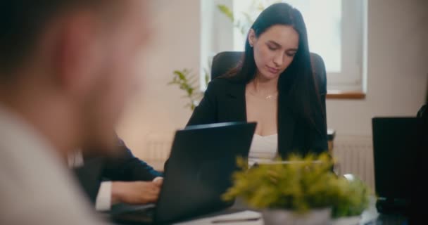 Grave giovane manager donna che utilizza tablet digitale mentre è seduto con i colleghi alla scrivania in ufficio. - Filmati, video