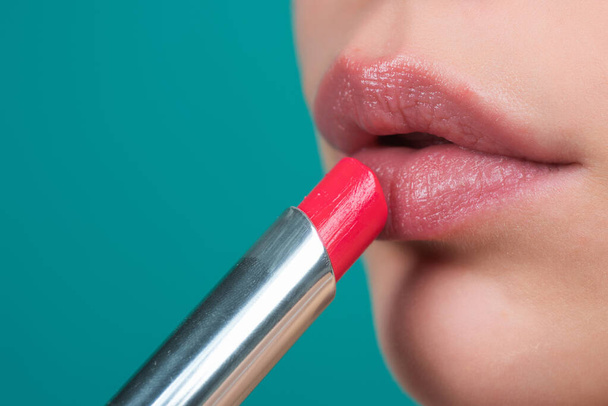 Red lipstick. Glossy make-up for plump natural lips. Lipstick and pomade. Close up red lips. Pink lipstick. Pomade. Applying lipstick. Make up in process - 写真・画像