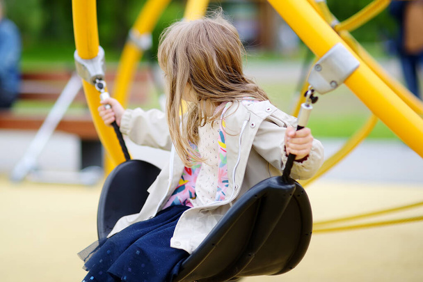 Little girl having fun on outside playground. Spring/summer/autumn active sport leisure for kids. Child on swing. Outdoor activity for children. Equipment for playground and entertainment park - Fotoğraf, Görsel