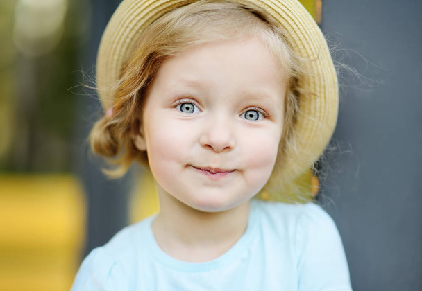 Cute toddler girl outdoors portrait in summer day. Smiling and charming child. Little lady with blonde and curly hair - Photo, image