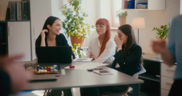 Повільний рух усміхнених жіночих колег обговорюється, сидячи за столом в офісі. - Кадри, відео