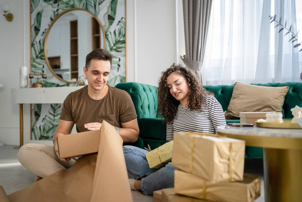 Pár muž a žena připravit dárky pro dovolenou kavkazský muž a žena balení dárky pro přátele pomocí balicí papír šťastný úsměv držet dárkové krabice doma skuteční lidé kopírovat prostor - Fotografie, Obrázek