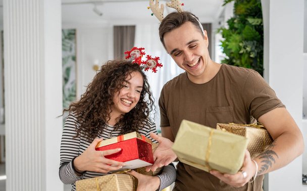 woman young adult caucasian female standing at home with gift box presents holding in hands while her boyfriend or husband man give boxes happy smile real people celebrate surprise love concept - Fotó, kép