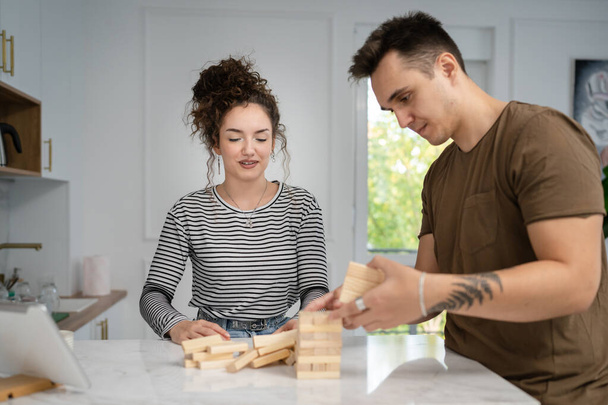 woman and man happy caucasian couple husband and wife or friends playing jenga table game at home having fun happy smile leisure time spending time together family time copy space real people - Foto, imagen