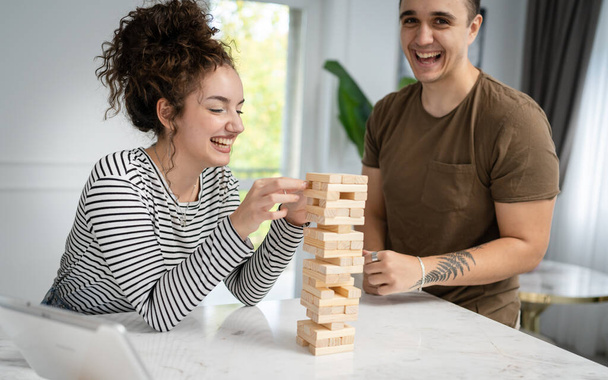 nainen ja mies onnellinen valkoihoinen pari aviomies ja vaimo tai ystävät pelaavat jenga pöytäpeli kotona hauskaa onnellinen hymy vapaa-aikaa viettää aikaa yhdessä perheen aikaa kopioi tilaa oikeita ihmisiä - Valokuva, kuva
